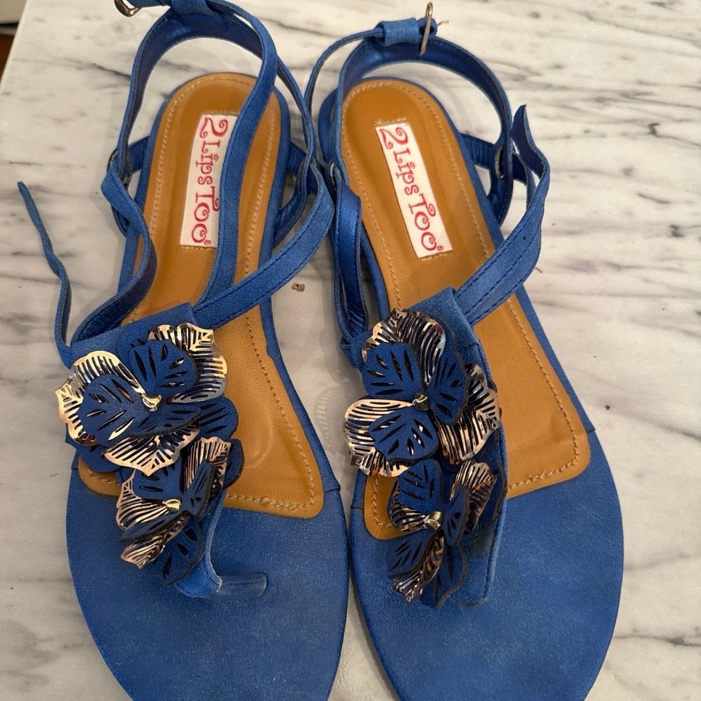 Royal Blue Flat Sandals with Floral Embellishment and Adjustable Ankle Strap.